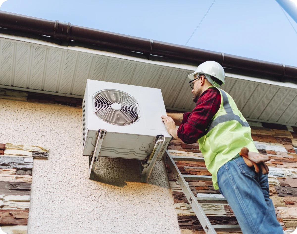 Worker inspecting outdoor air conditioning unit.