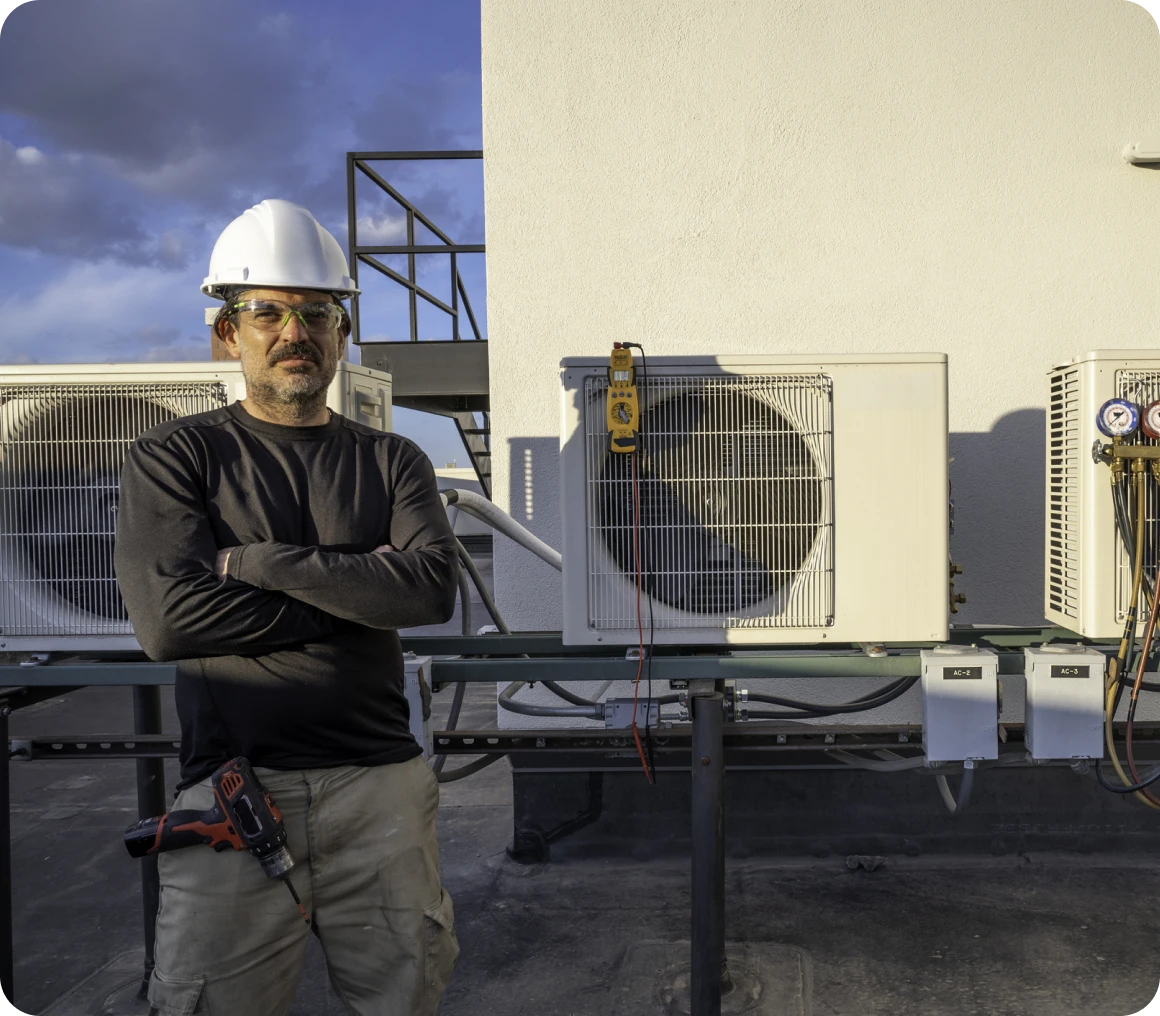 Worker standing by rooftop air conditioning units.